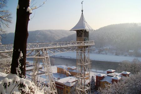 Schneebedeckte Landschaft mit einem Aussichtsturm und einem Fluss im Hintergrund.