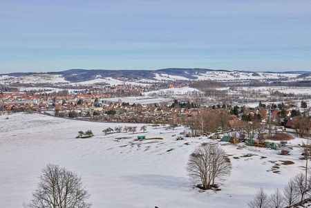 Schneebedeckte Landschaft mit Bergen im Hintergrund und einem klaren blauen Himmel.