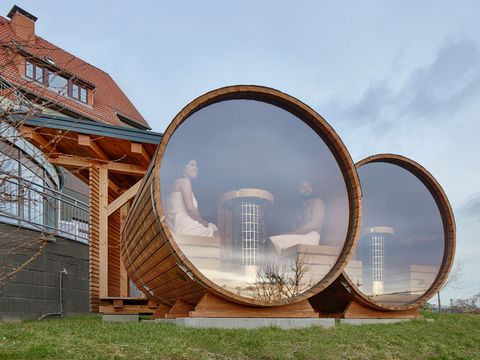 Saunafässer von Außen mit Menschen die auf Landschaft blicken.