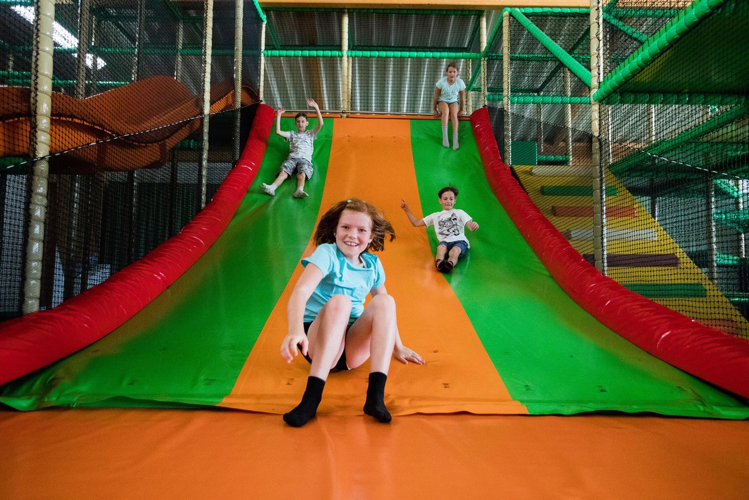 Kinder rutschen fröhlich von einer bunten Rutsche in einem Indoor-Spielplatz, dem Solivital Sebnitz