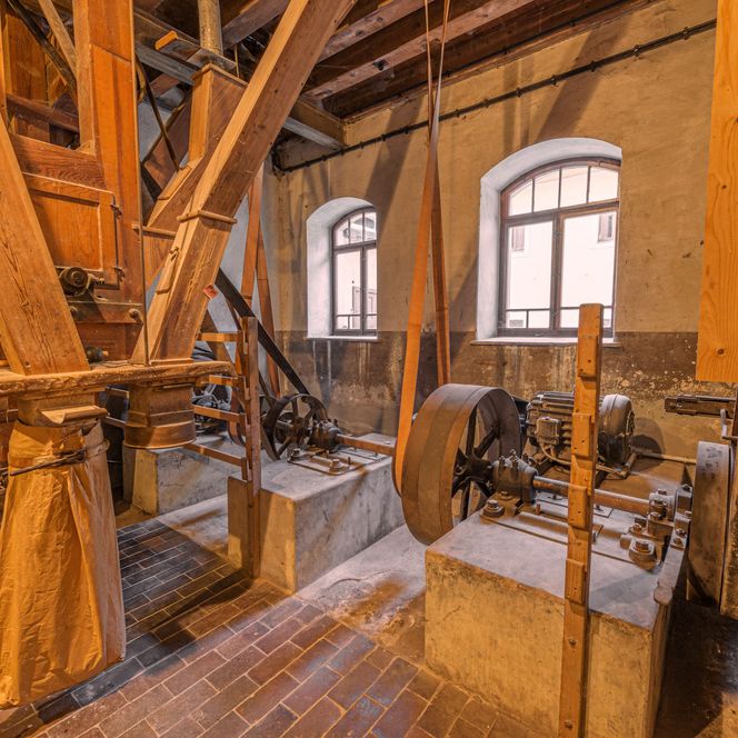 Historischer Maschinenraum mit Holz- und Metallteilen, Fenstern und sichtbaren Werkzeugen.