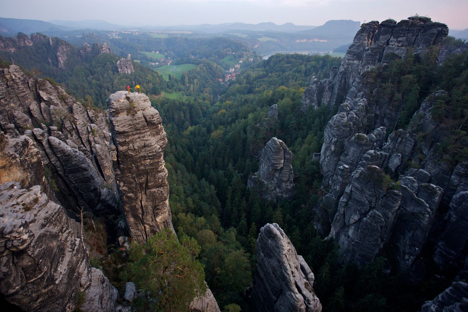 Steile Felsklippen mit dichtem Wald und Tal im Hintergrund.