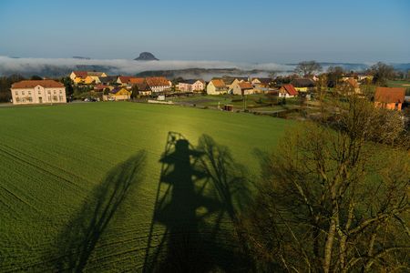 Grünes Feld mit Häusern im Hintergrund und einem klaren blauen Himmel.