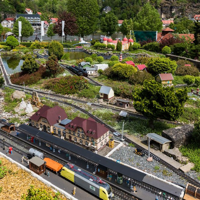 Detailreiche Modelllandschaft mit Miniaturbahnhof, Zügen und grüner Vegetation.
