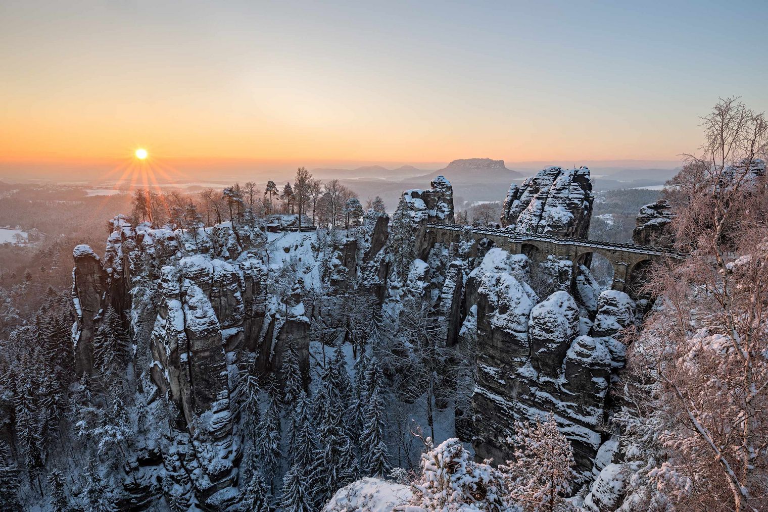 Felsen und Basteibrücke im Winter mit Schnee zum Sonnenuntergang