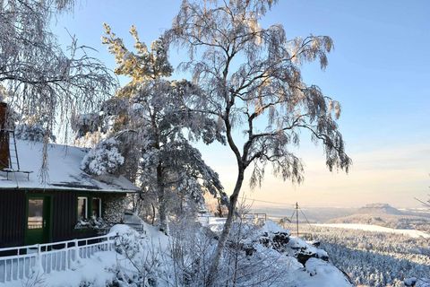 Gasthaus auf Bergspitze mit schneebedeckten Bäumen und blauem Himmel.
