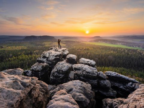 Waldlandschaft mit Blick auf Pfaffenstein, blauer Himmel, sanfte Hügel.