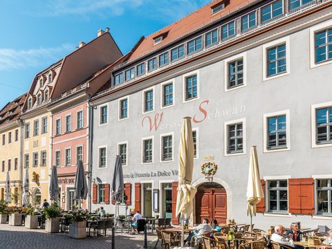 Historischer Marktplatz in Pirna mit bunten Gebäuden und Restaurants bei klarem Himmel.