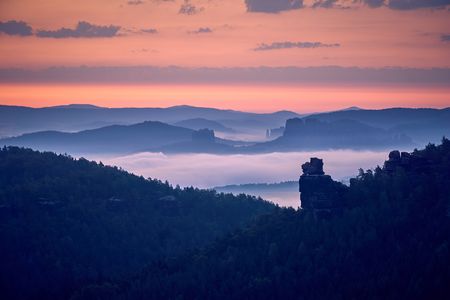 Felsformation Hunskirche im Nebel, beleuchtet von einem farbenfrohen Sonnenuntergang.