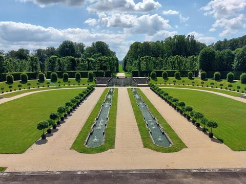 Symmetrischer Gartenanlage des Barockgarten Großsedlitz mit grünen Rasenflächen, Hecken und Wasserbecken unter blauem Himmel.