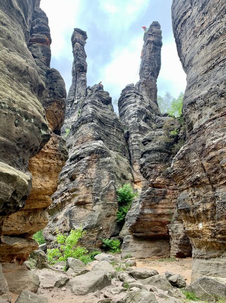 Drei hohe, schmale Felsen ragen zwischen steilen Wänden aus Sandstein in den Himmel.