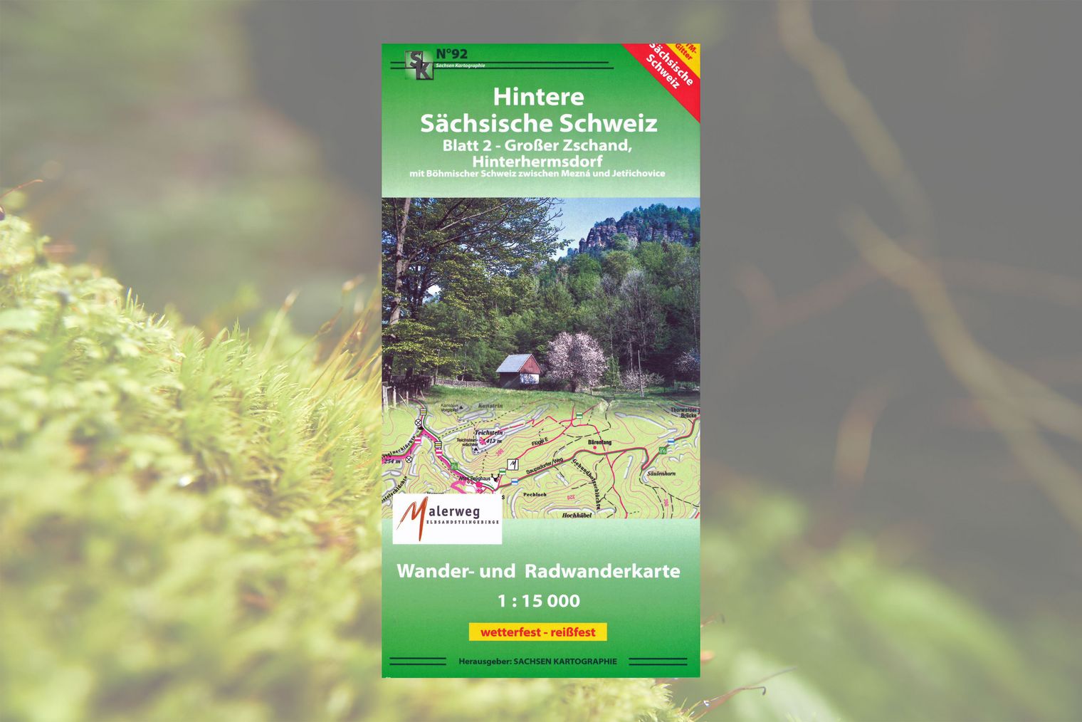 Titelseite Wanderkarte mit grünem Rahmen und Foto von kleinem Haus umgeben von Wald und Felsen.