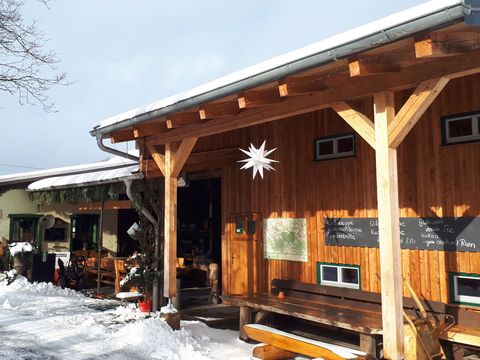 Verschneite Außenterrasse an einem Holzhaus.