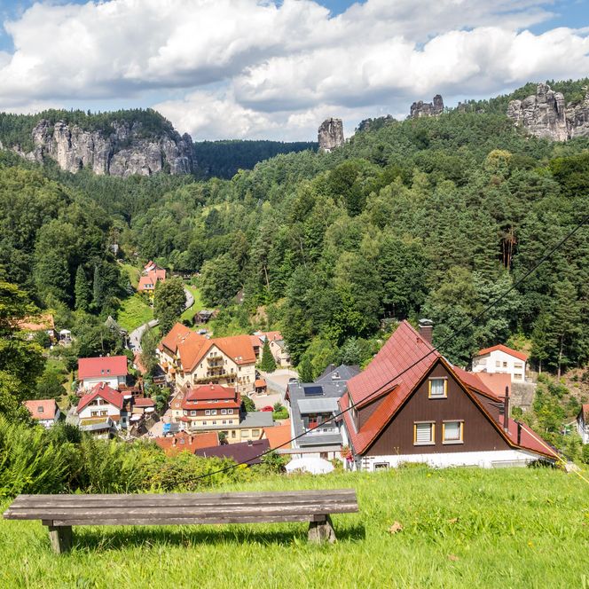 Blick auf ein malerisches Dorf mit bunten Häusern, umgeben von grünen Wäldern und Felsen.
