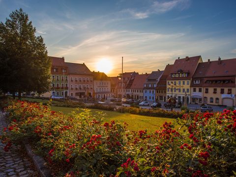 Marktplatz Stolpen bei Sonnenuntergang, historische Gebäude im Hintergrund.