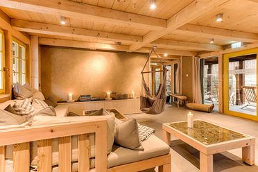 Gemütlicher Raum mit Holzdekor, bequemen Sofas, einem Tisch und einer Hängematte. Sanfte Beleuchtung. Winterdorf Schmilka