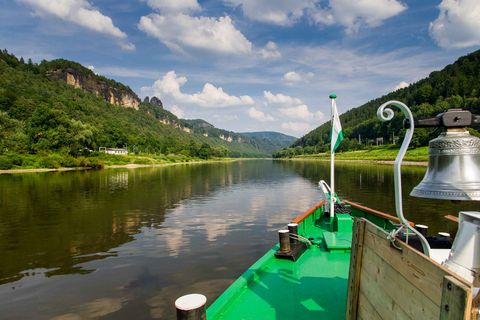 Dampfer auf der Elbe, umgeben von grünen Hügeln und blauen Himmel mit Wolken.