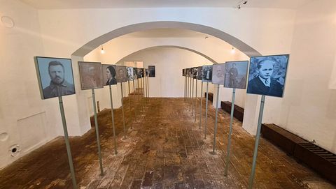 Ausstellungsraum mit mehreren Portraits von Opfern der nationalsozialistischen Krankenmorde auf Ständern, Wände in neutralem Weiß, Boden aus Holz.