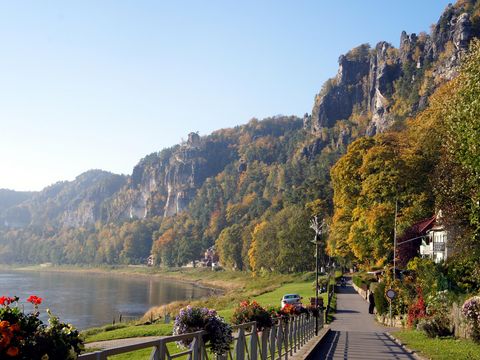 Promenade Kurort Rathen an der Elbe mit Gebäuden und blauem Himmel.
