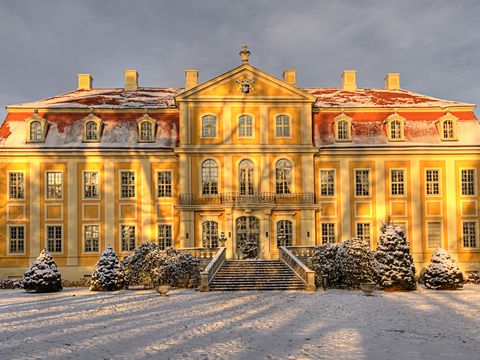 Barockschloss Rammenau Barockschloss Rammenau, angeleuchtet von Sonnen, schneebedeckter Garten.