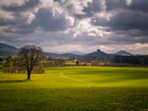 Felsformation Zirkelstein mit Wiesen im Vordergrund, bewölkter Himmel darüber.