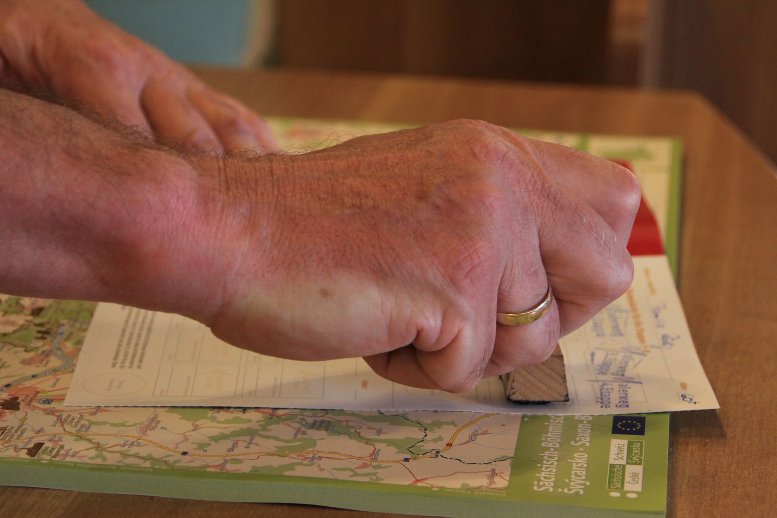 Eine Hand hält einen Stift und schreibt auf einem Blatt Papier, das auf einer Karte liegt.