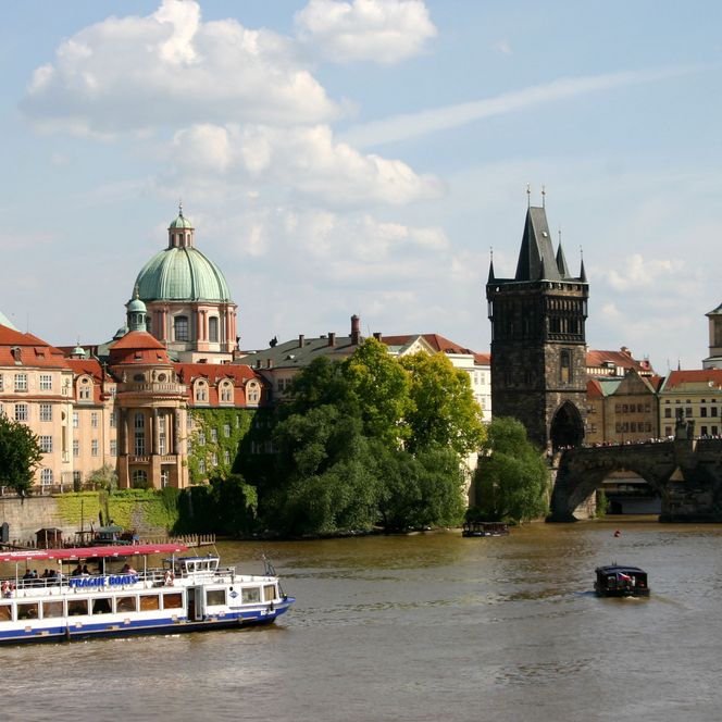 Blick auf ein historisches Stadtbild mit Gebäuden und einem Fluss, Boot auf dem Wasser.
