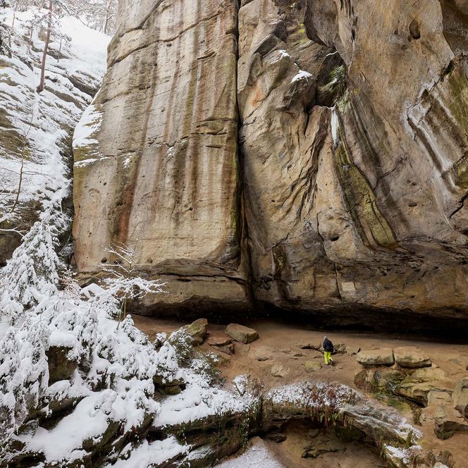 Felswand der Gautschgrotte mit schneebedecktem Boden und vereisten Stellen.