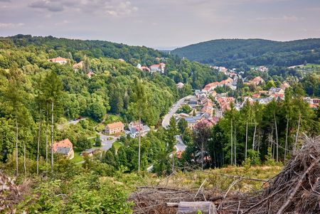 Blick auf ein Dorf umgeben von Wäldern und Hügeln, mit Häusern und Straßen im Vordergrund.