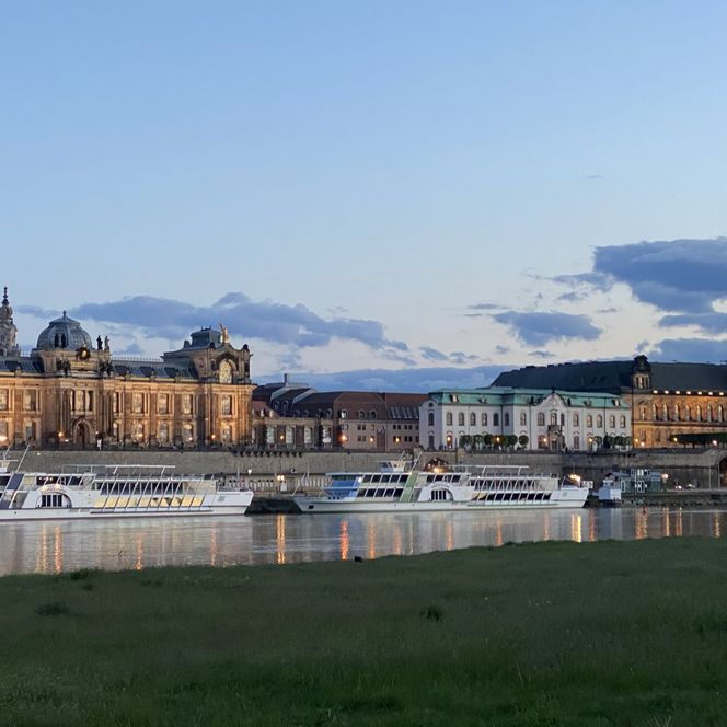 Panoramaansicht von Dresden mit historischen Gebäuden und der Elbe im Vordergrund.