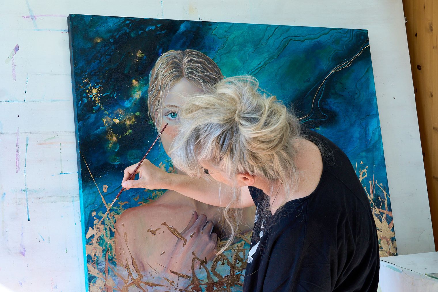 Künstlerin Yvonne Brückner malt an einem Bild auf einer großen Leinwand.