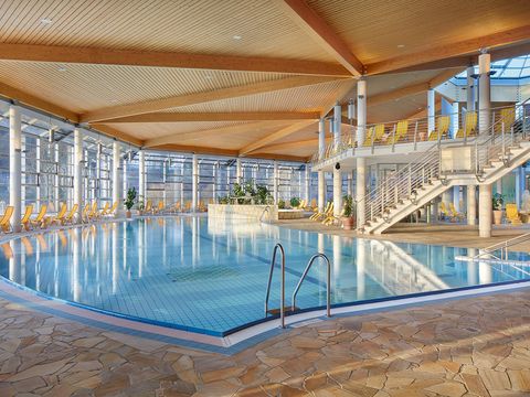 Innenbereich der Therme mit großem Pool, hohen Fenstern und einer Kuppeldecke.