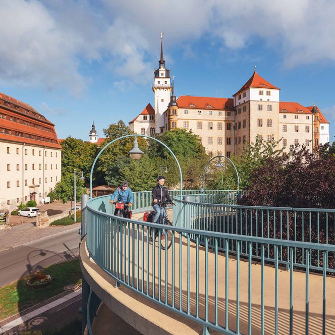Stadtansicht mit Gebäuden, Bäumen und einem blauen Himmel mit Wolken.