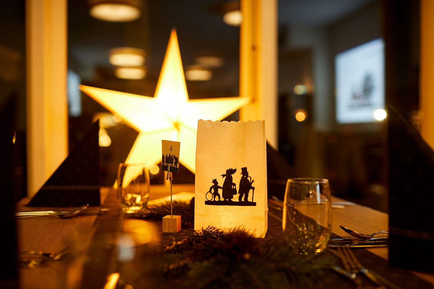 Ein Tisch mit einer Weihnachtsstern-Dekoration und einer Karte mit einer silhouettierten Szene.