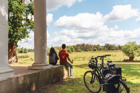 Junge sitzt auf einer Säule auf dem Sieglitzer Berg, blickt auf eine Wiese, neben ihm steht ein Fahrrad.
