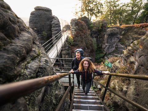 Zwei Personen laufen Treppe in Felsen Landschaft nach oben.