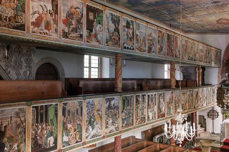 Blick auf eine Kirche mit bunten Wandmalereien und Holzbalustraden.