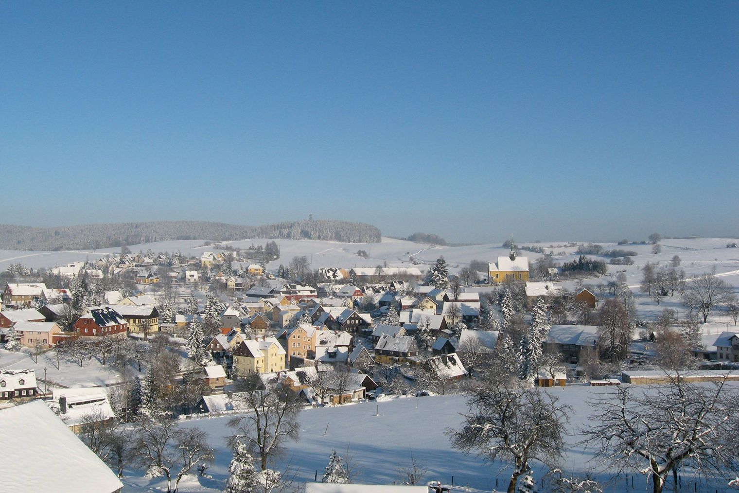Dorf in winterlicher Landschaft mit Schnee, blauer Himmel