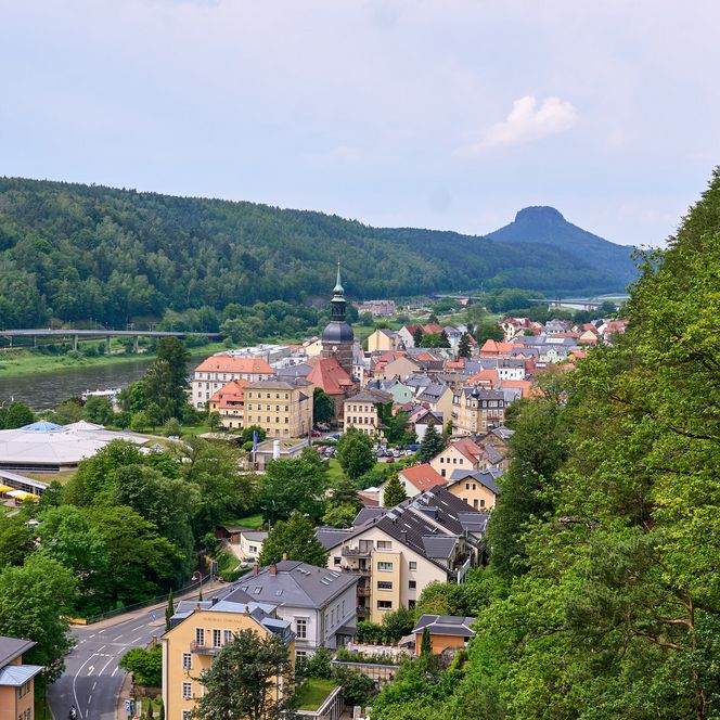 Blick auf eine Stadt mit grünen Hügeln und einem Berg im Hintergrund.