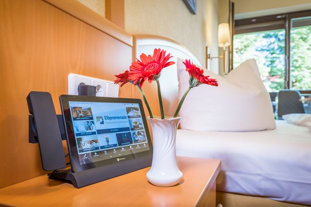 Blick auf den Nachttisch eines Hotelzimmers mit Blumen und Telefon.