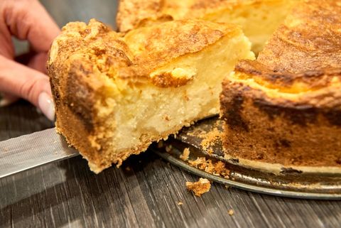 Ein Stück Eierschecke (sächsischer Käsekuchen) wird mit einem Messer aus der Form geschnitten.