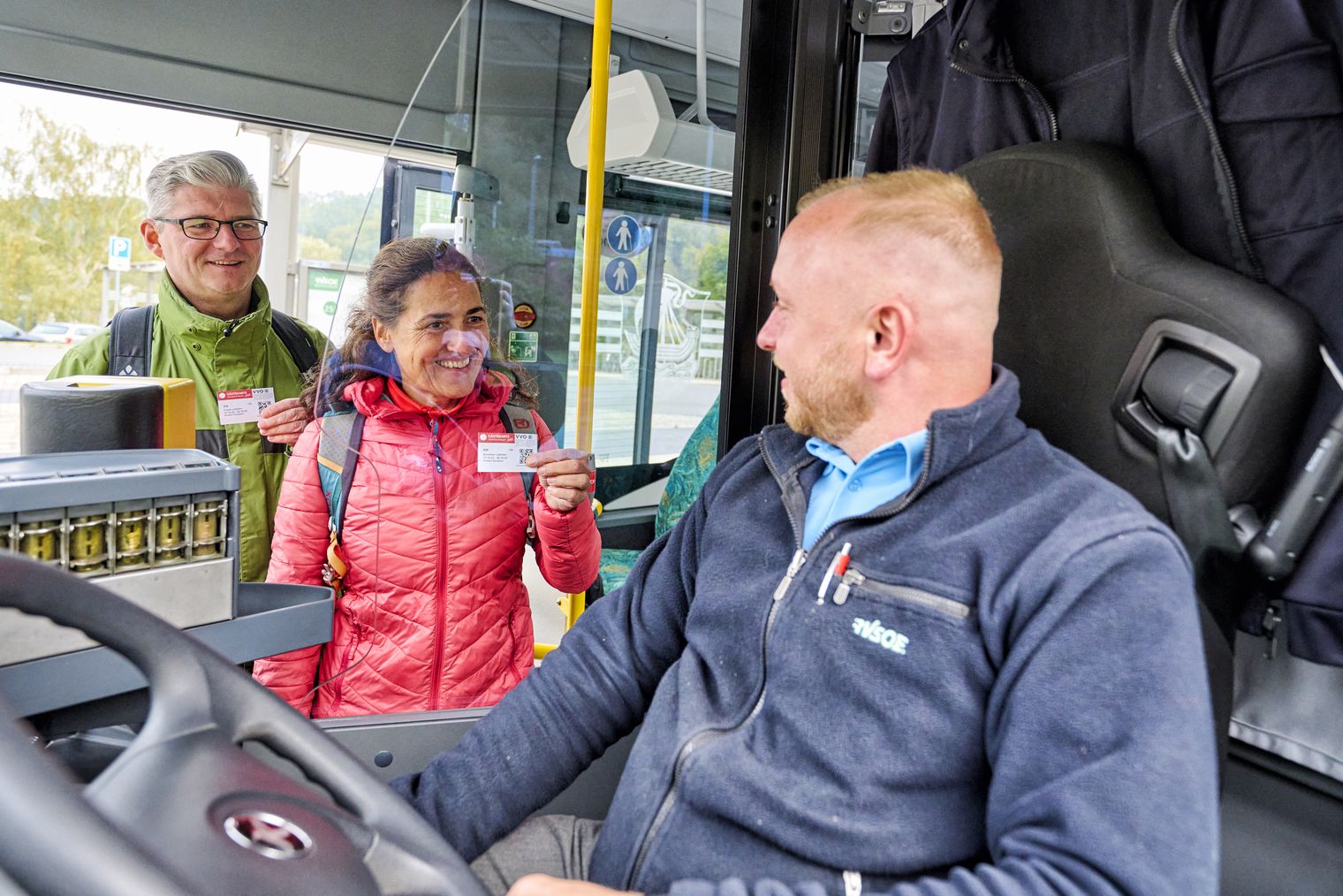 Zwei Personen steigen in einen Bus ein und zeigen dem Busfahrer zur Kontrolle die Gästekarte Sächsische Schweiz mobil.