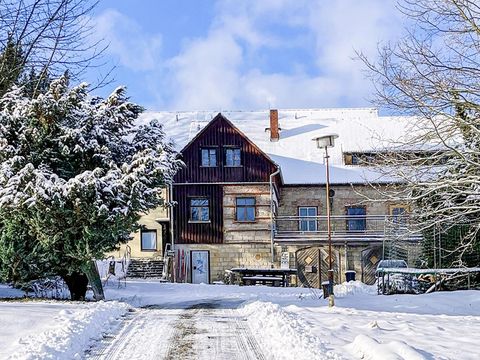 Winterlandschaft mit schneebedecktem Häuschen und Bäumen im Hintergrund.