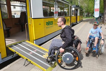 Rollstuhlfahrer benutzen eine Rampe an einer Straßenbahnhaltestelle der Kirnitzschtalbahn..
