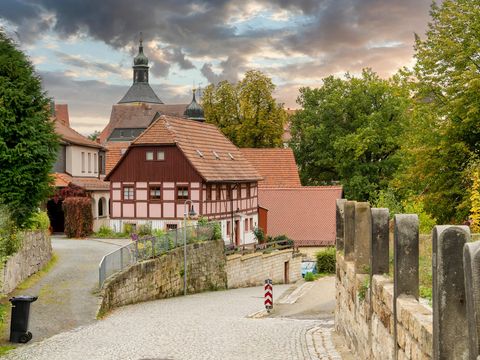 Burg Hohnstein mit alten Fachwerkhäusern, umgeben von grünen Bäumen.