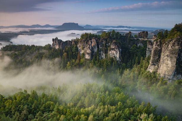 Nebelverhangene Felsformationen der Sächsischen Schweiz mit Blick auf bewaldete Täler.