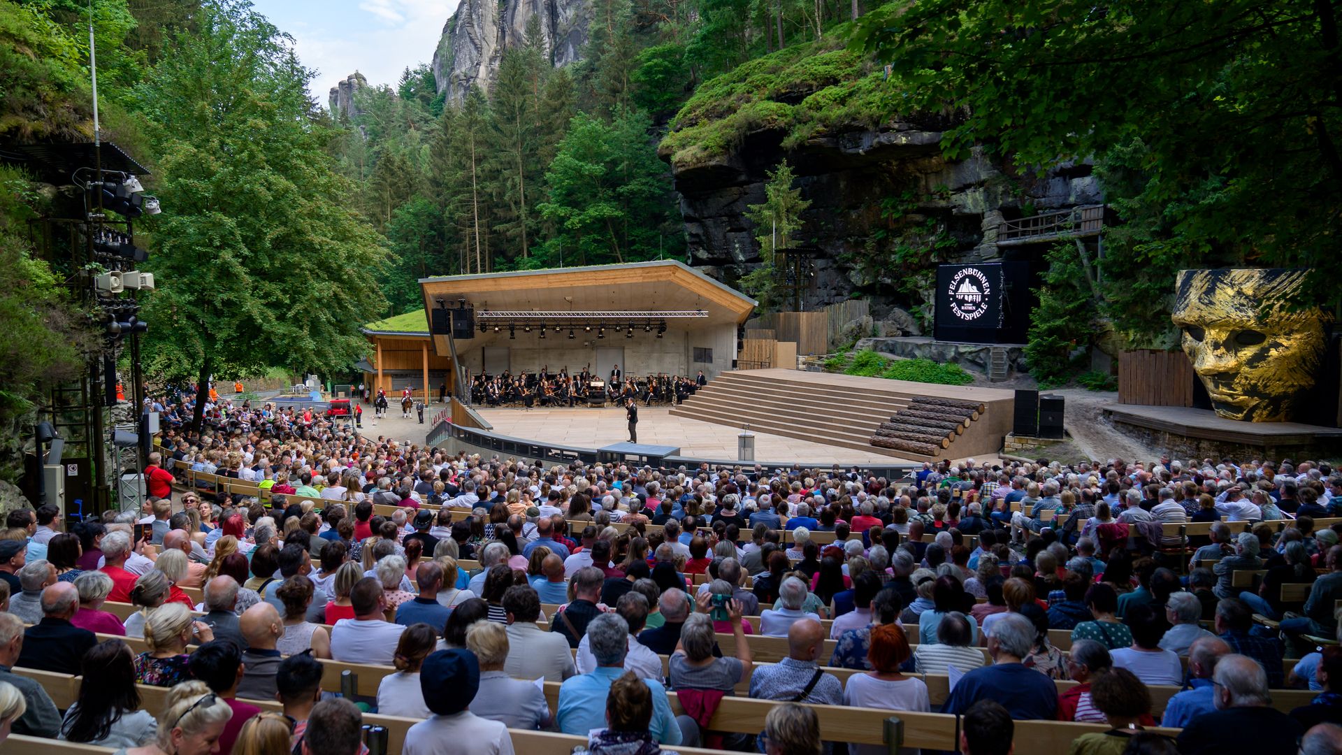 Felsenbühne Rathen: Vollbesetztes Freilufttheater in einer natürlichen Umgebung mit Bäumen und Felsen im Hintergrund.