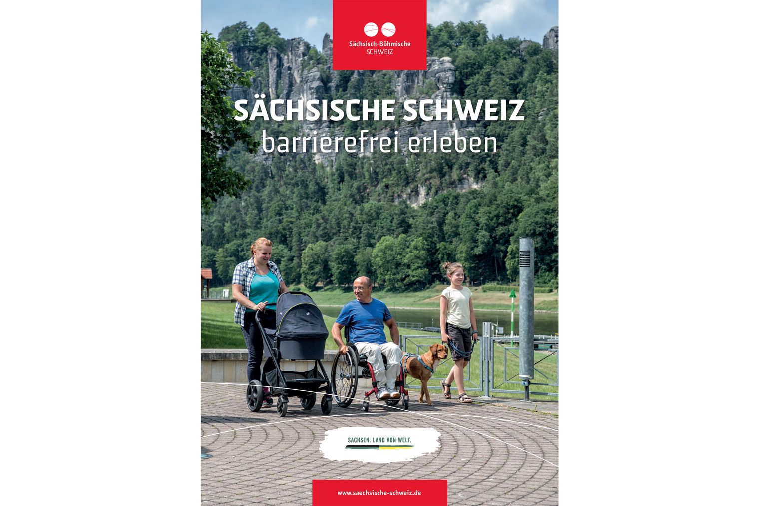 Familie, Rollstuhlfahrer, Kind mit Laufrad, Hund und Kinderwagen vor einem großen Felsmassiv.