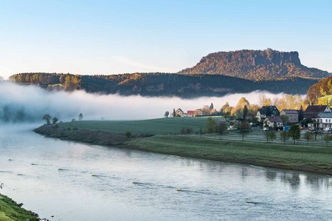 Blick auf einen Fluss mit Nebel, im Hintergrund ein markanter Berg und eine bewaldete Landschaft.